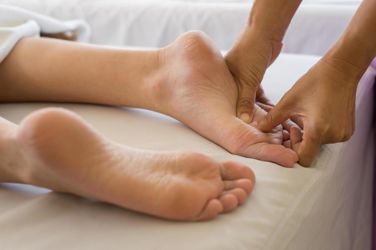 primo piano della donna che fa massaggio ai piedi presso la spa foto