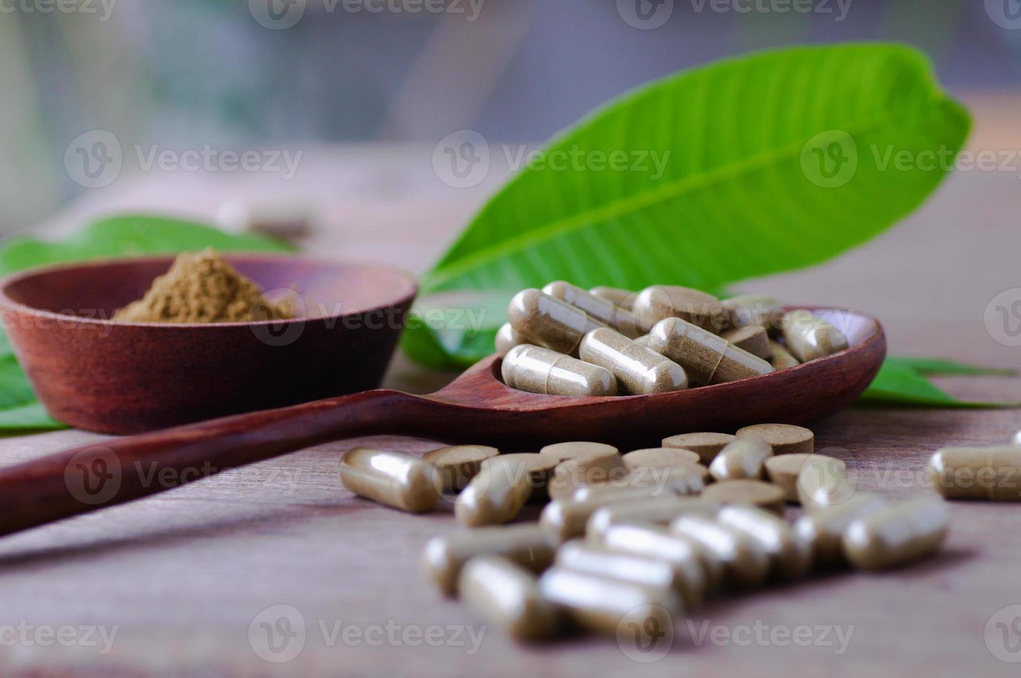 capsula pillola a base di erbe sul tavolo di legno con foglie verdi foto