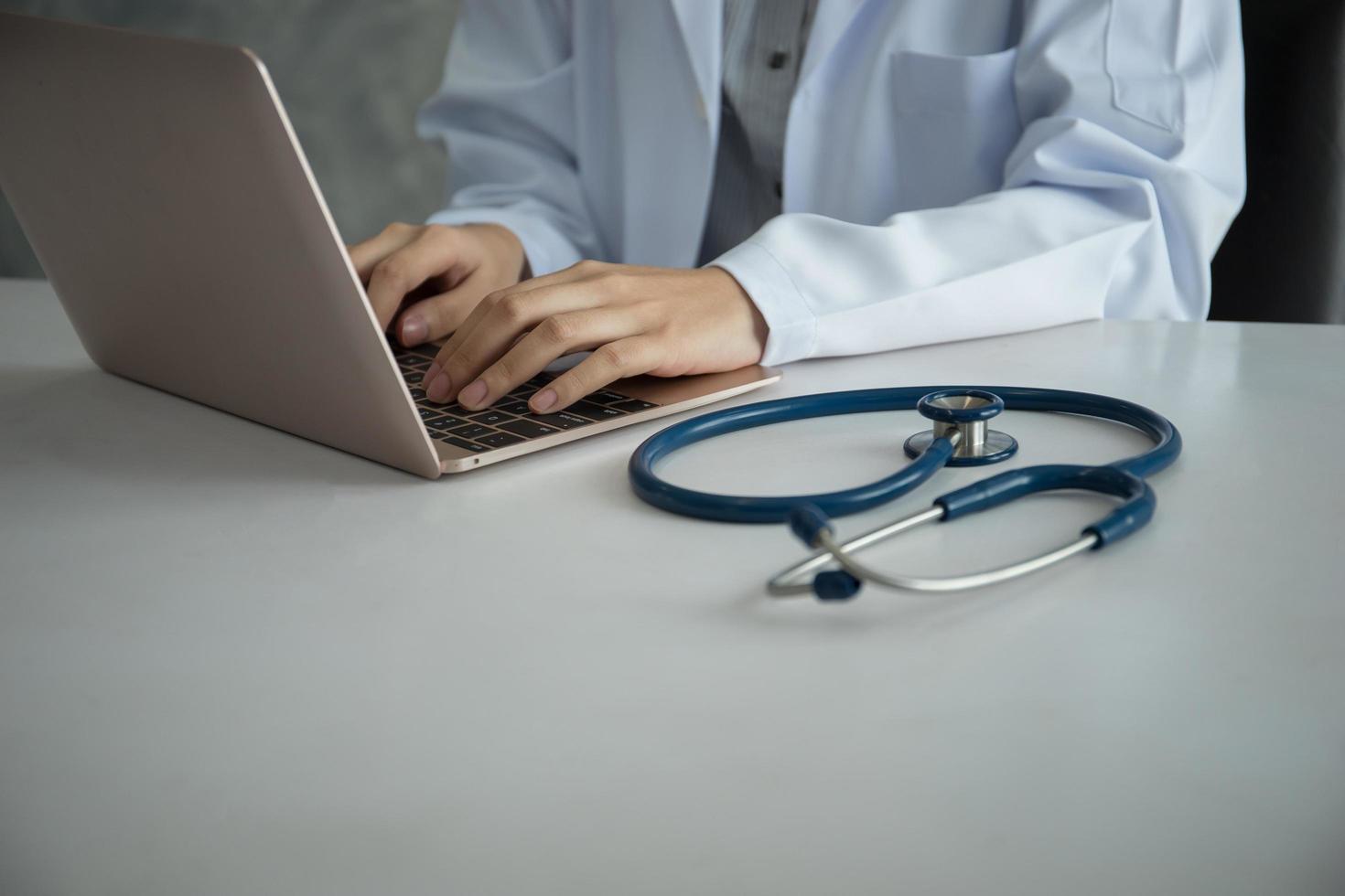 primo piano del medico che lavora con il computer portatile in ufficio foto