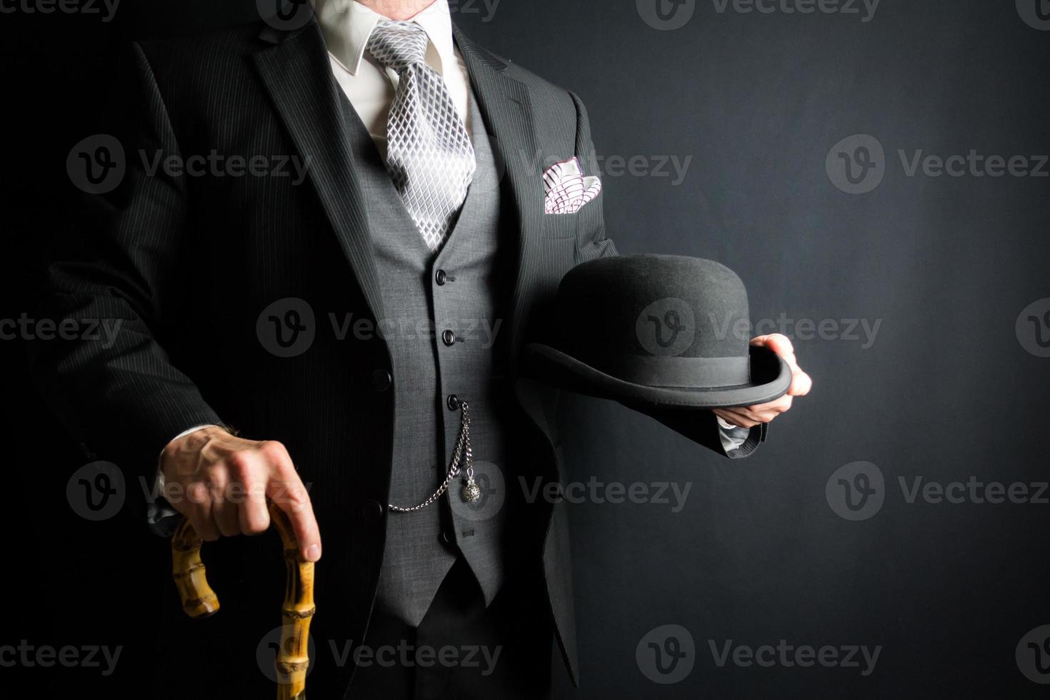 uomo nel buio grigio completo da uomo Tenere giocatore di bowling cappello e ombrello su nero sfondo. Vintage ▾ stile e retrò moda di elegante inglese signore. foto