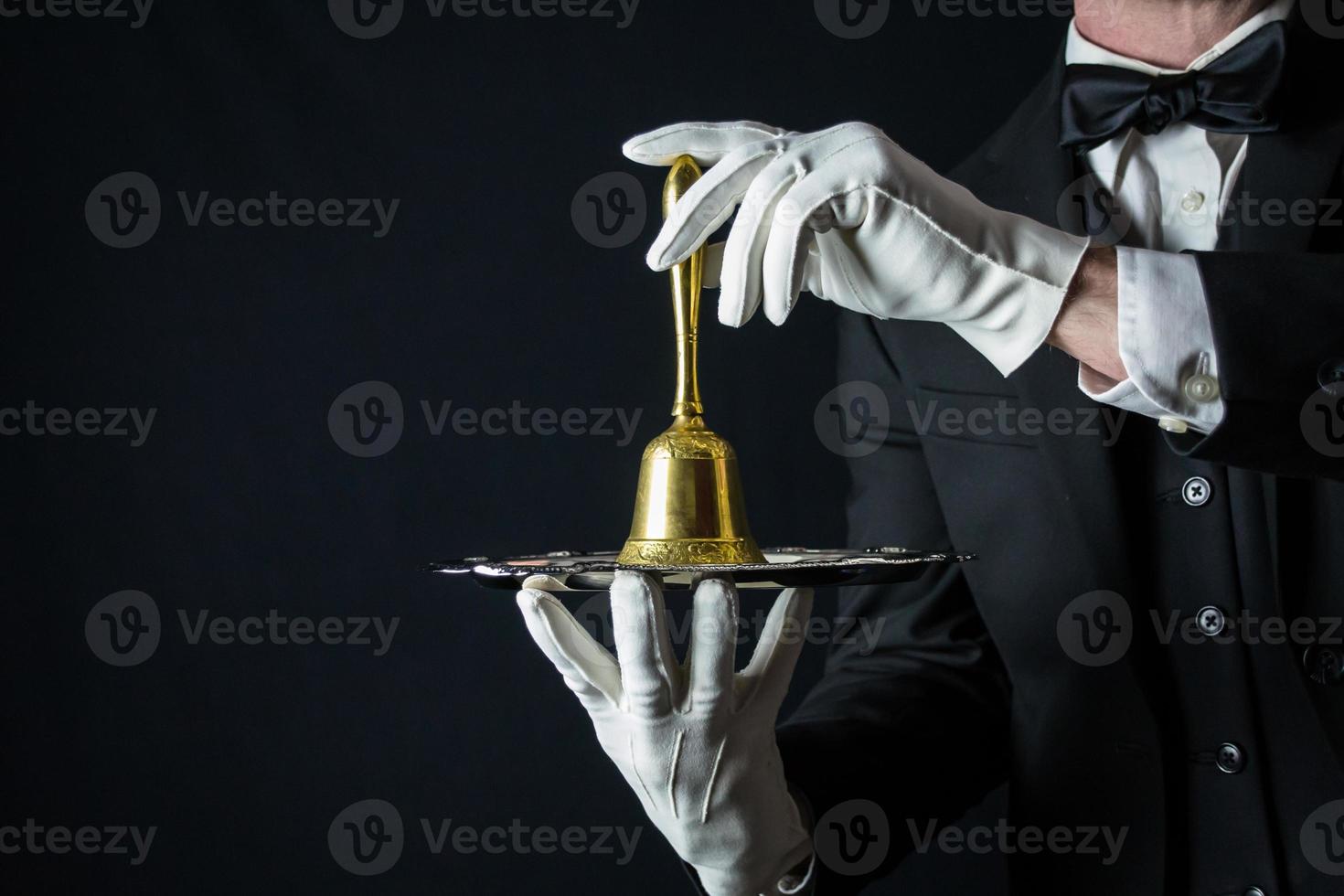 ritratto di maggiordomo nel bianca guanti e buio completo da uomo Tenere oro campana su argento vassoio. copia spazio per servizio industria e professionale ospitalità. foto