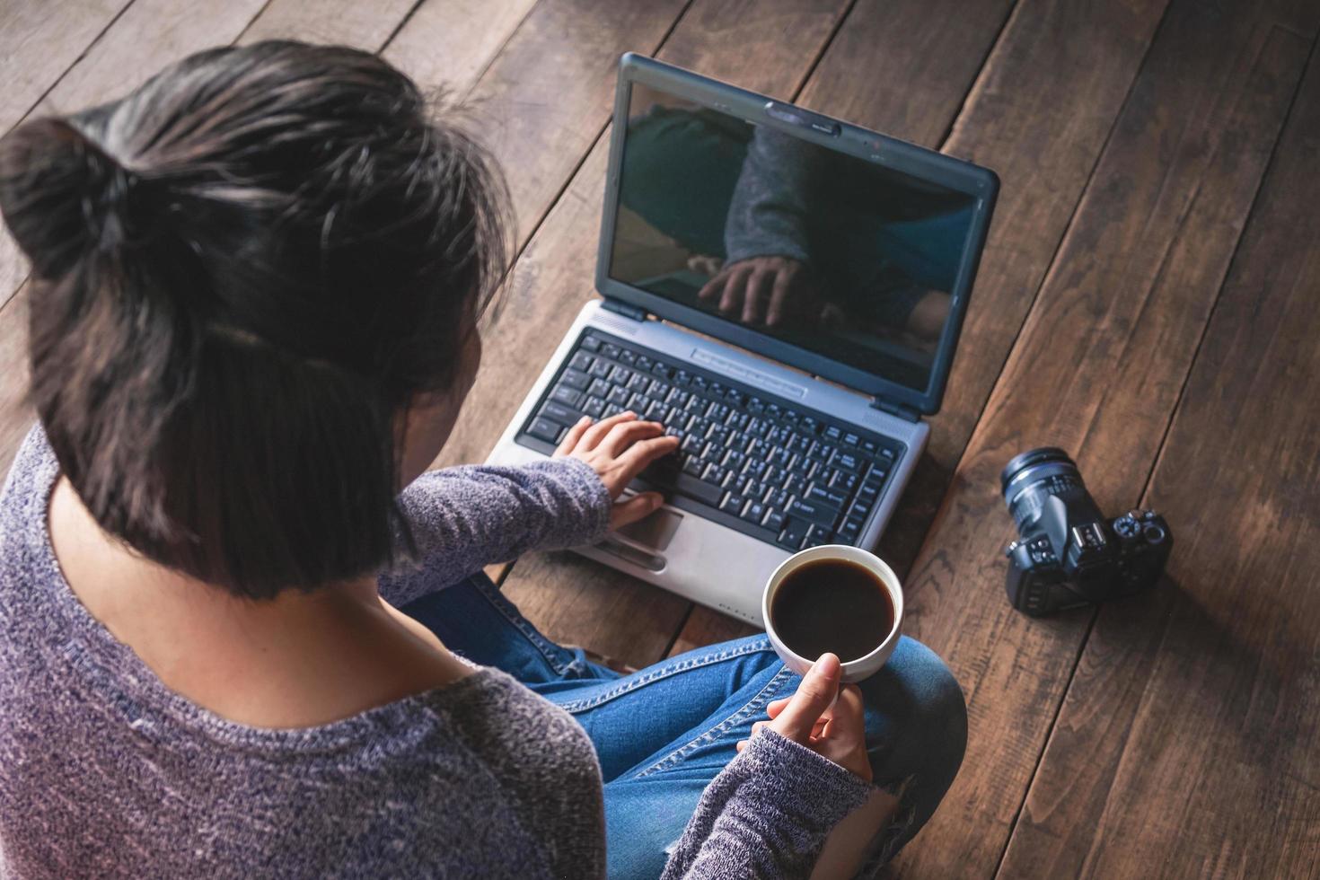 donna che lavora su un computer portatile con un caffè e una macchina fotografica foto