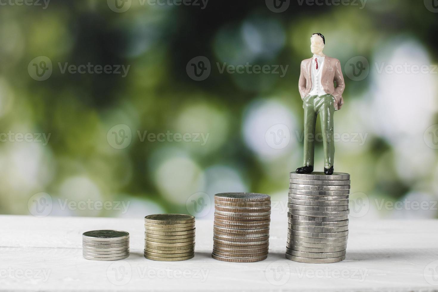 figurina di persona d'affari in piedi su pile di denaro foto