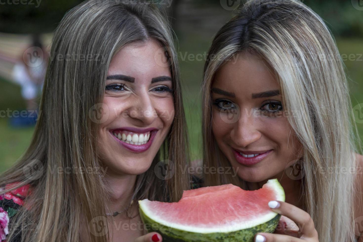 coppia di giovane bellissimo donne mangiare un' fetta di fresco anguria foto