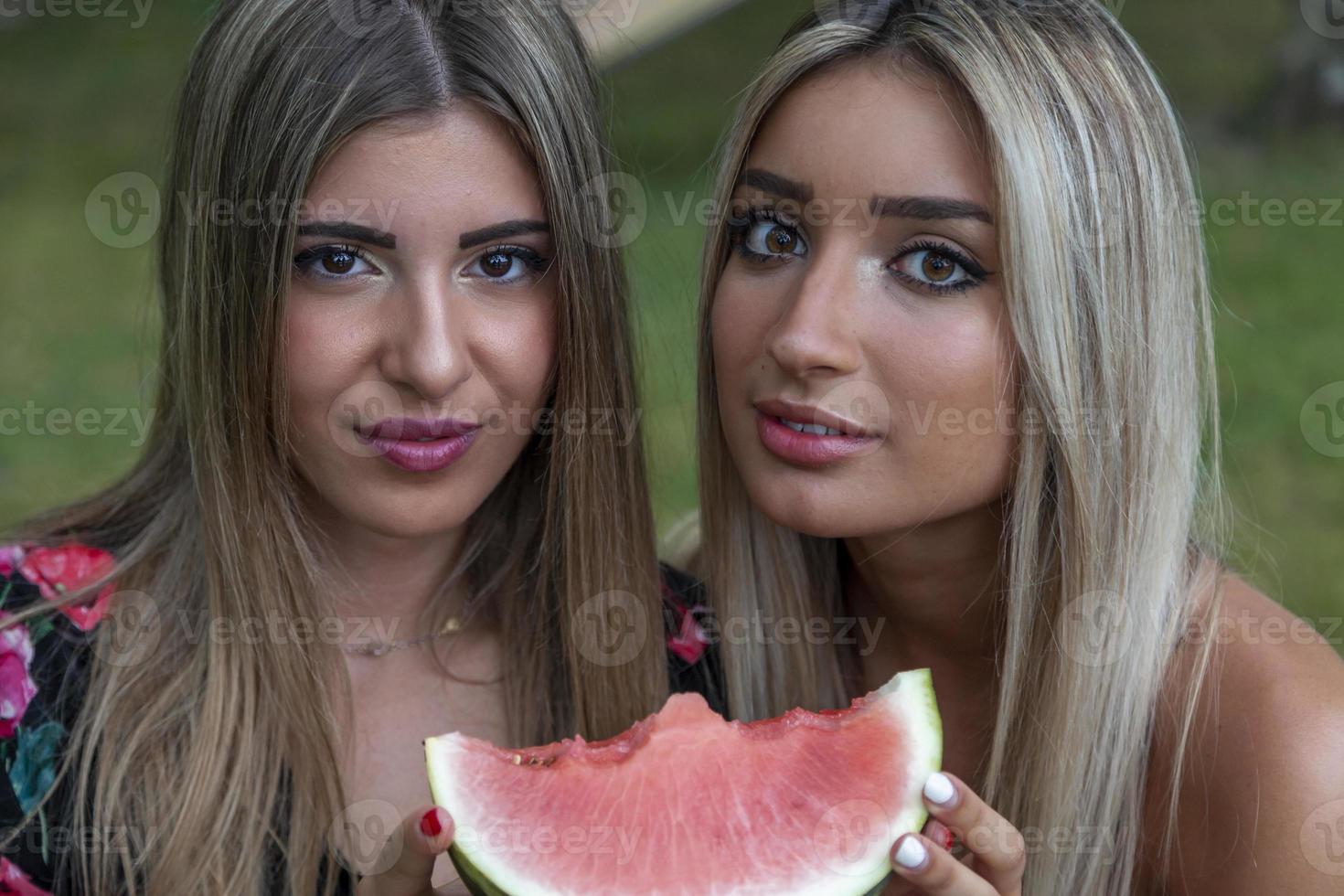 coppia di giovane bellissimo donne mangiare un' fetta di fresco anguria foto