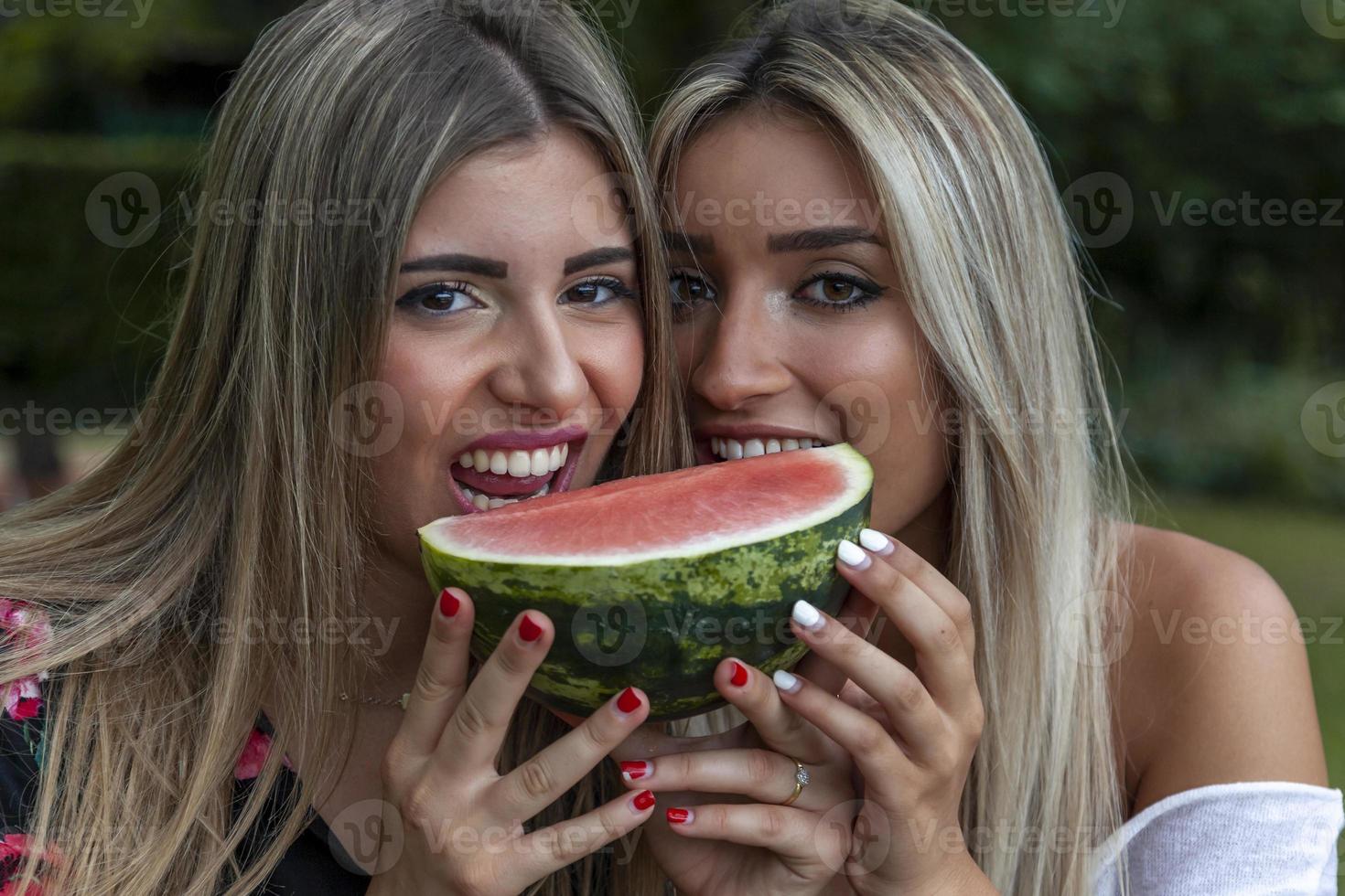 coppia di giovane bellissimo donne mangiare un' fetta di fresco anguria foto