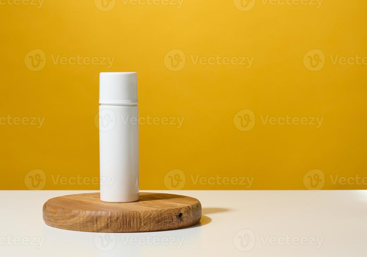 bianca plastica il giro tubo per cosmetici, creme e liquido gel su un' di legno podio, giallo sfondo foto