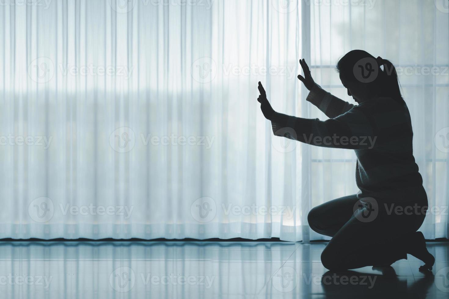 silhouette di donna in ginocchio e preghiere nel moderno Chiesa a tramonto volta. femmina cattolico preghiera culto per Dio desiderio un' meglio vita nel casa a alba con credere fede. concetto di adoratori in ginocchio. foto