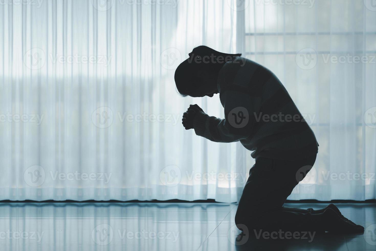 silhouette di donna in ginocchio e preghiere nel moderno Chiesa a tramonto volta. femmina cattolico preghiera culto per Dio desiderio un' meglio vita nel casa a alba con credere fede. concetto di adoratori in ginocchio. foto