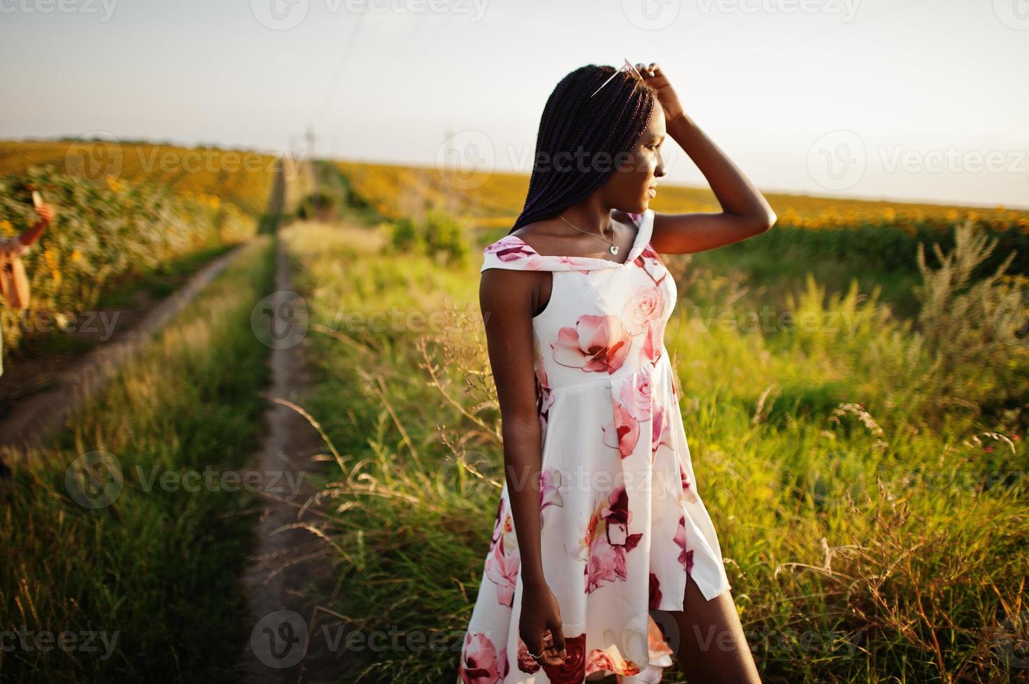 piuttosto giovane donna nera indossare abito estivo posa in un campo di girasoli. foto