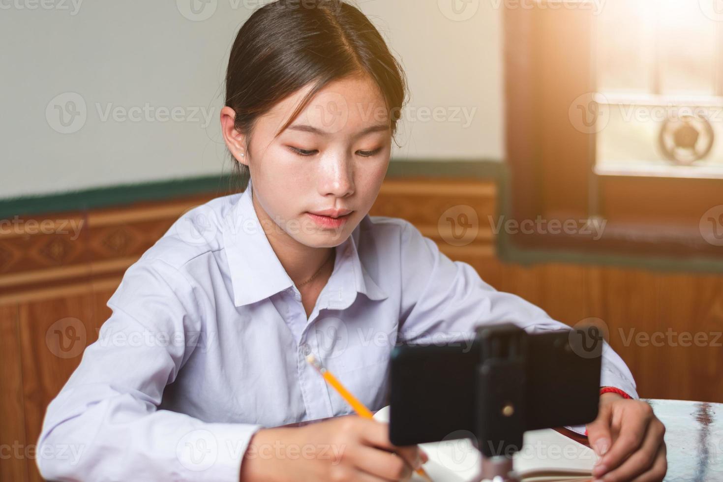 un' donne alunno con alunno completo da uomo è studiando in linea a partire dal mobile Telefono a casa con insegnante, Nota insegnanti spiegare conoscenza su il suo prenotare, formazione scolastica e in linea apprendimento concetto copia spazio per testo foto