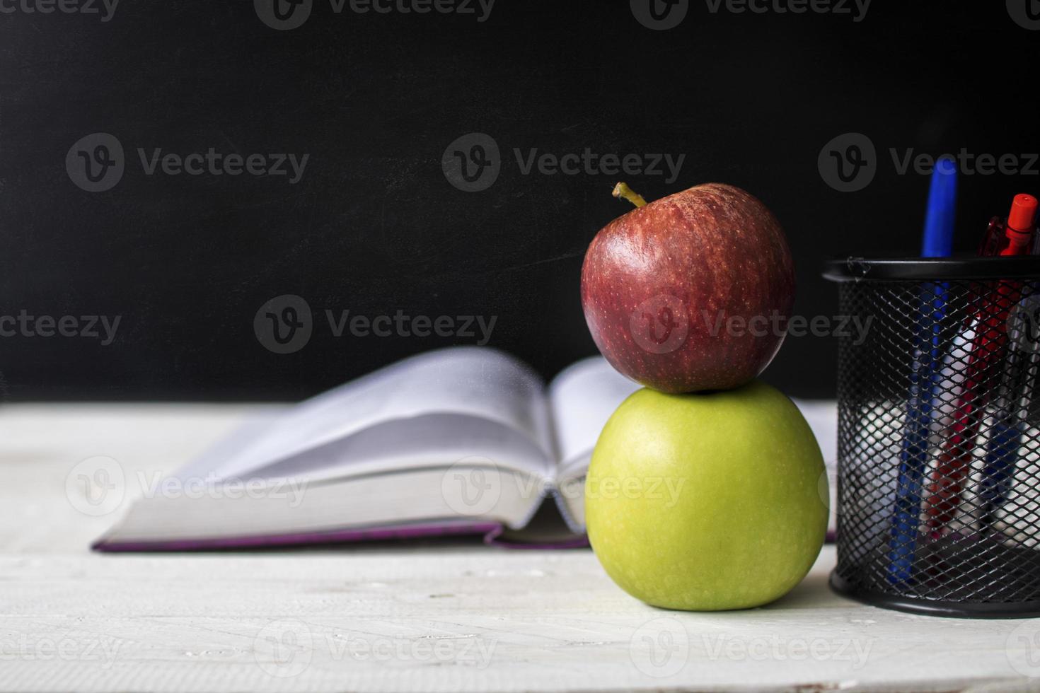 due mele su una scrivania con taccuino e penne foto
