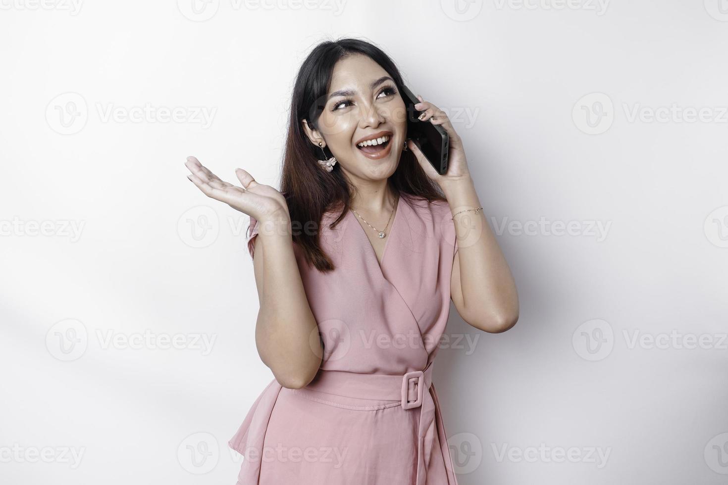 un' ritratto di un' contento asiatico donna vestito nel rosa e Tenere sua Telefono, isolato di bianca sfondo foto