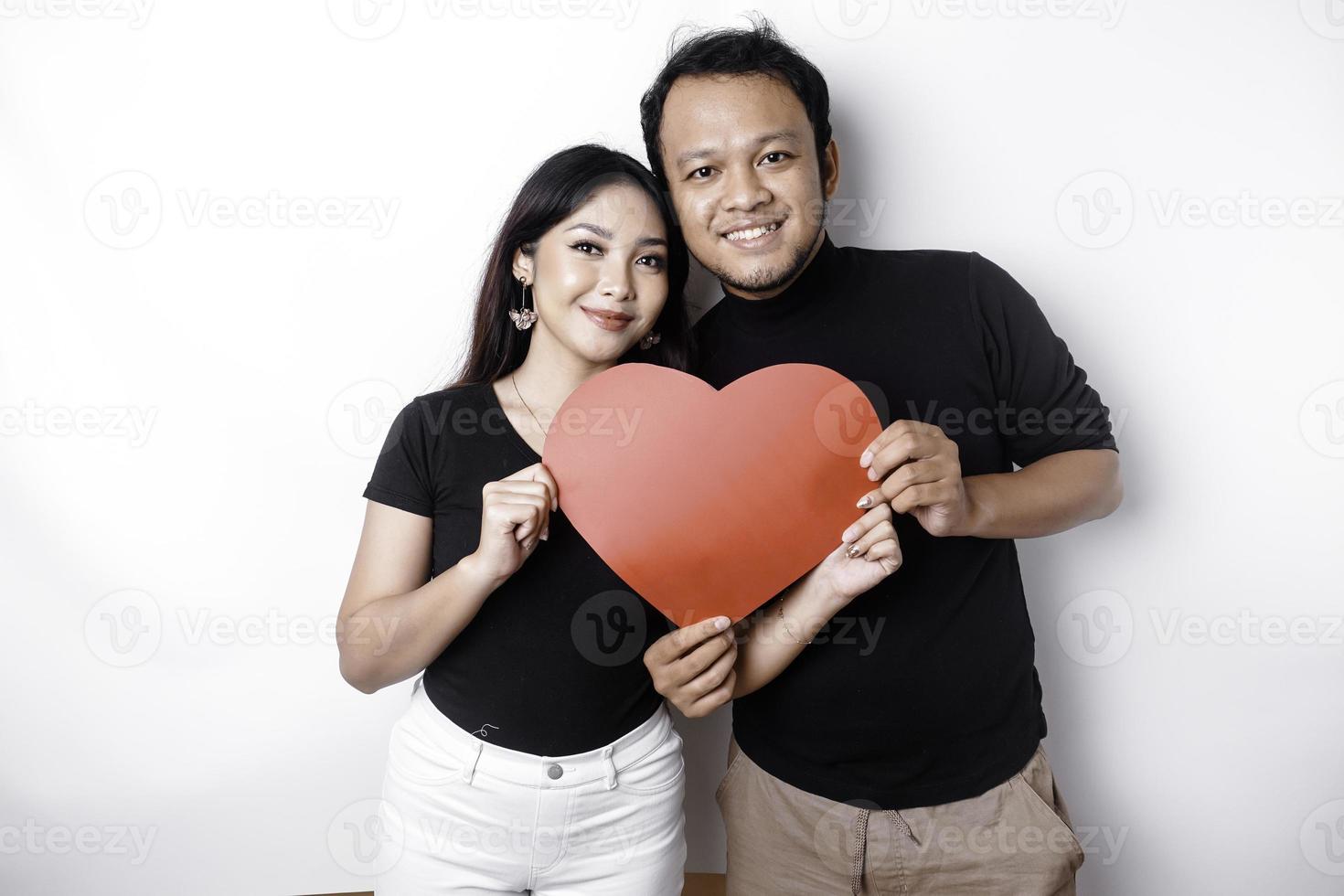 un' giovane asiatico coppia sorridente e Tenere rosso a forma di cuore carta, isolato di bianca sfondo foto