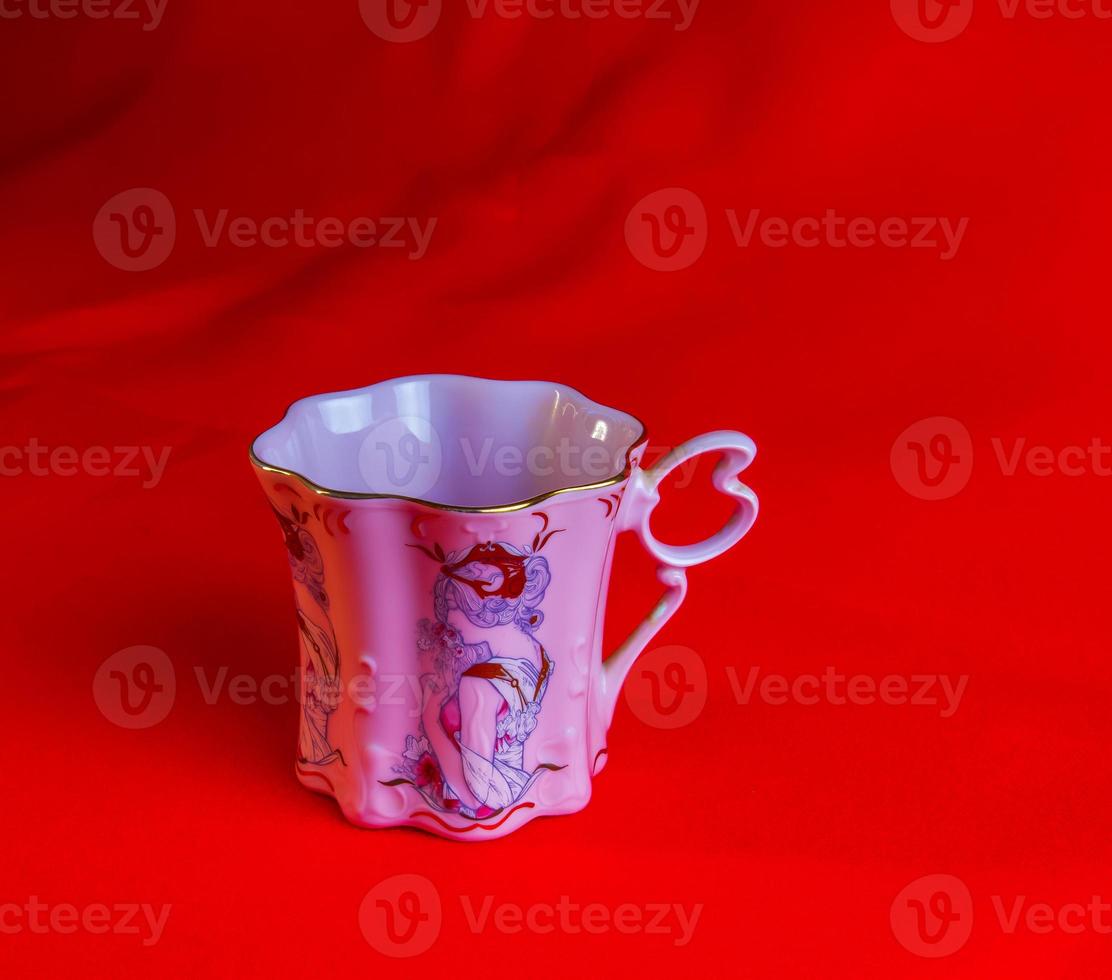 porcellana rosa tazza di un insolito forma è fatto nel il ceco repubblica. un' tazza con un' romantico modello su un' rosso sfondo. foto