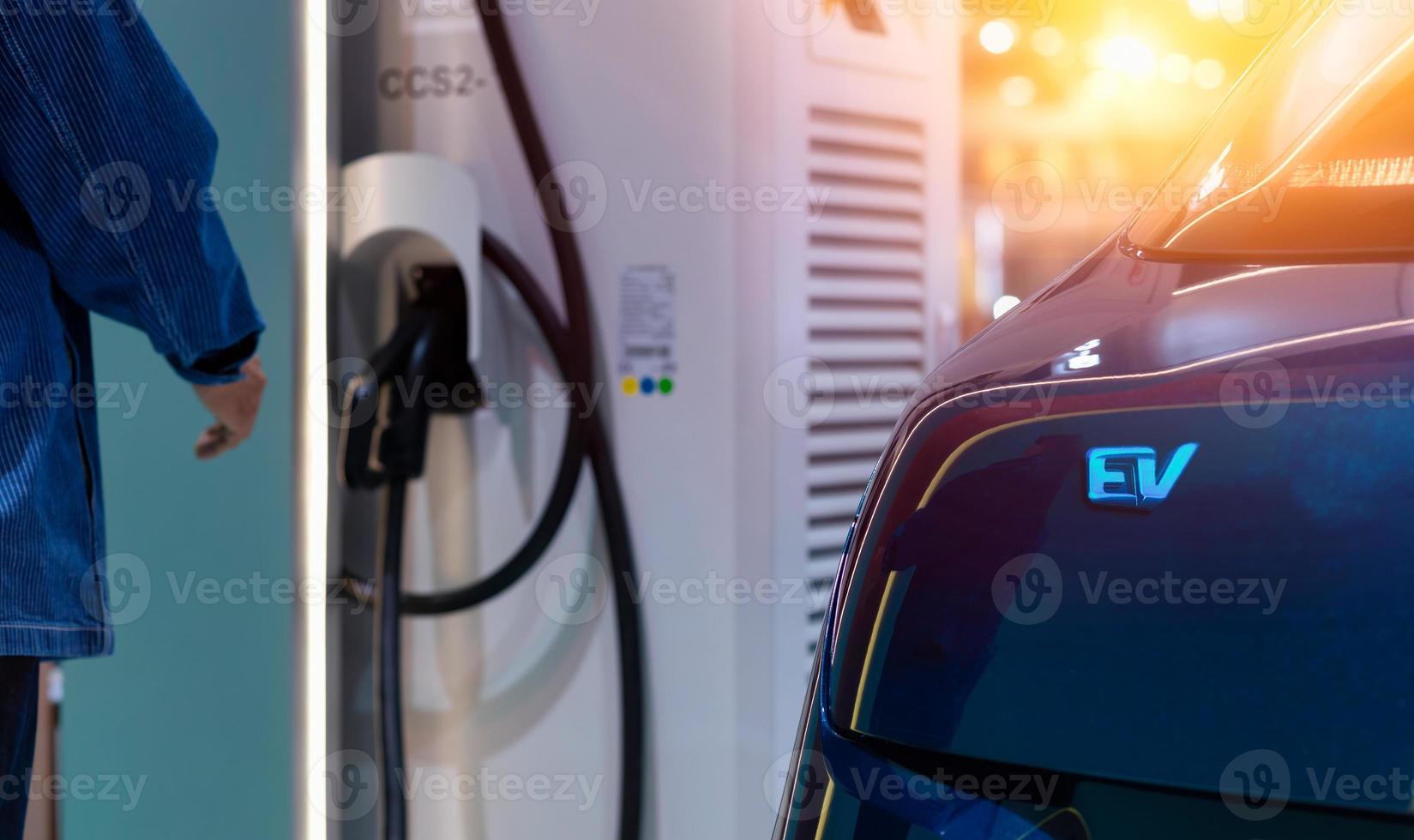 elettrico auto ricarica con stazione. uomo collegamento un' ricarica cavo per un' auto a partire dal un elettrico auto ricarica stazione. foto