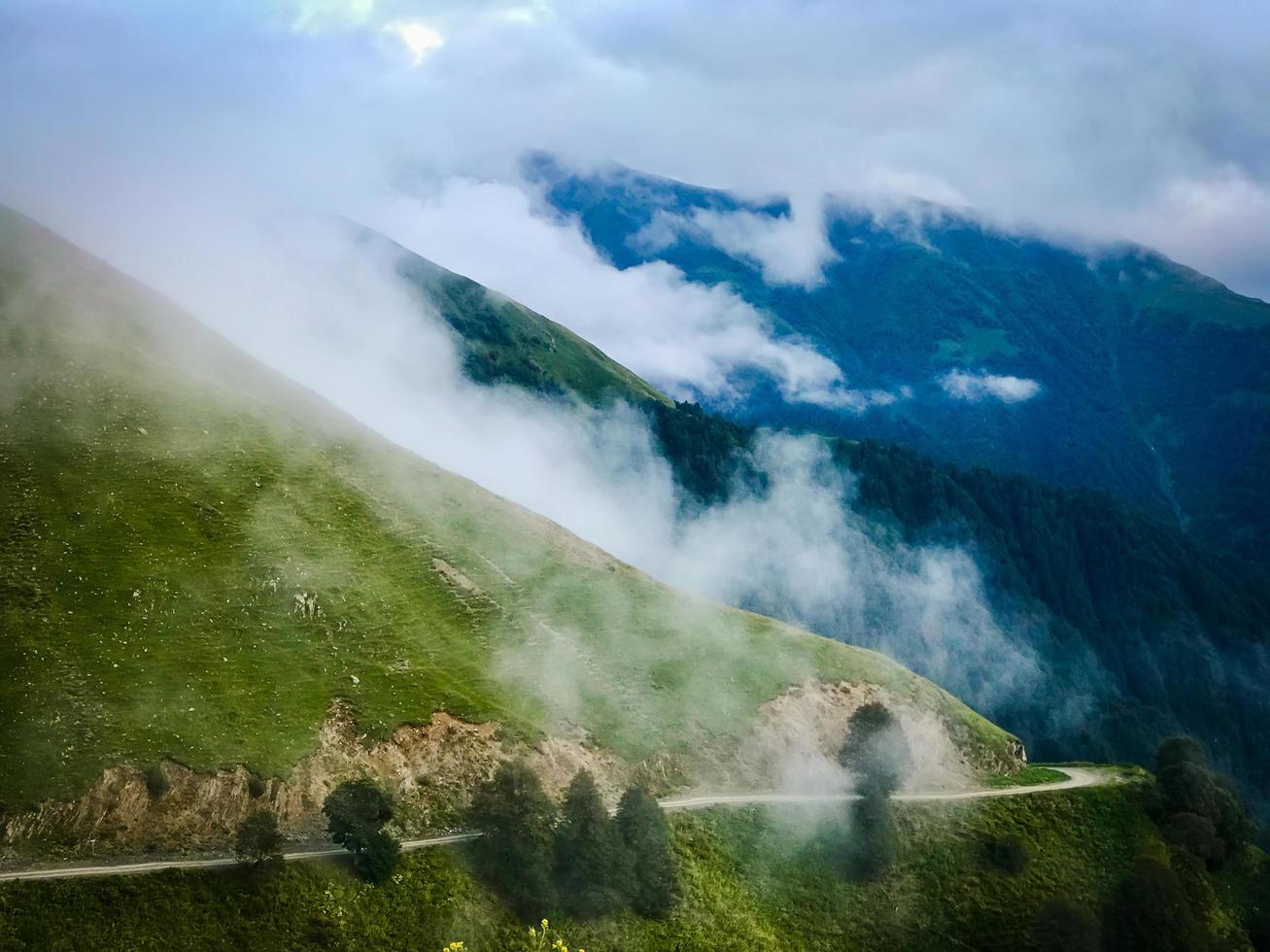panoramica strada sterrata di montagna nella regione tusheti circondata dalla natura nebbiosa del caucaso foto
