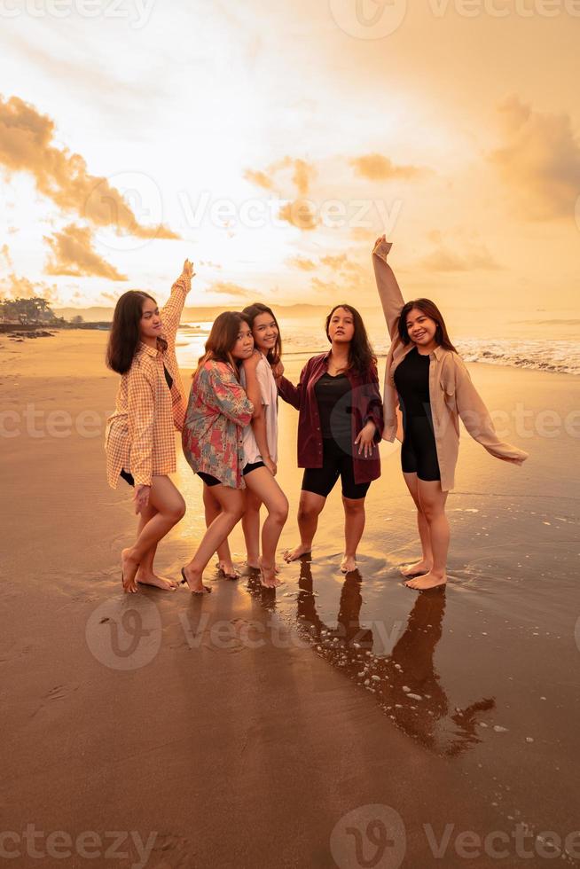 un' gruppo di asiatico donne nel camicie in posa felicemente mentre visitare un' bellissimo spiaggia foto