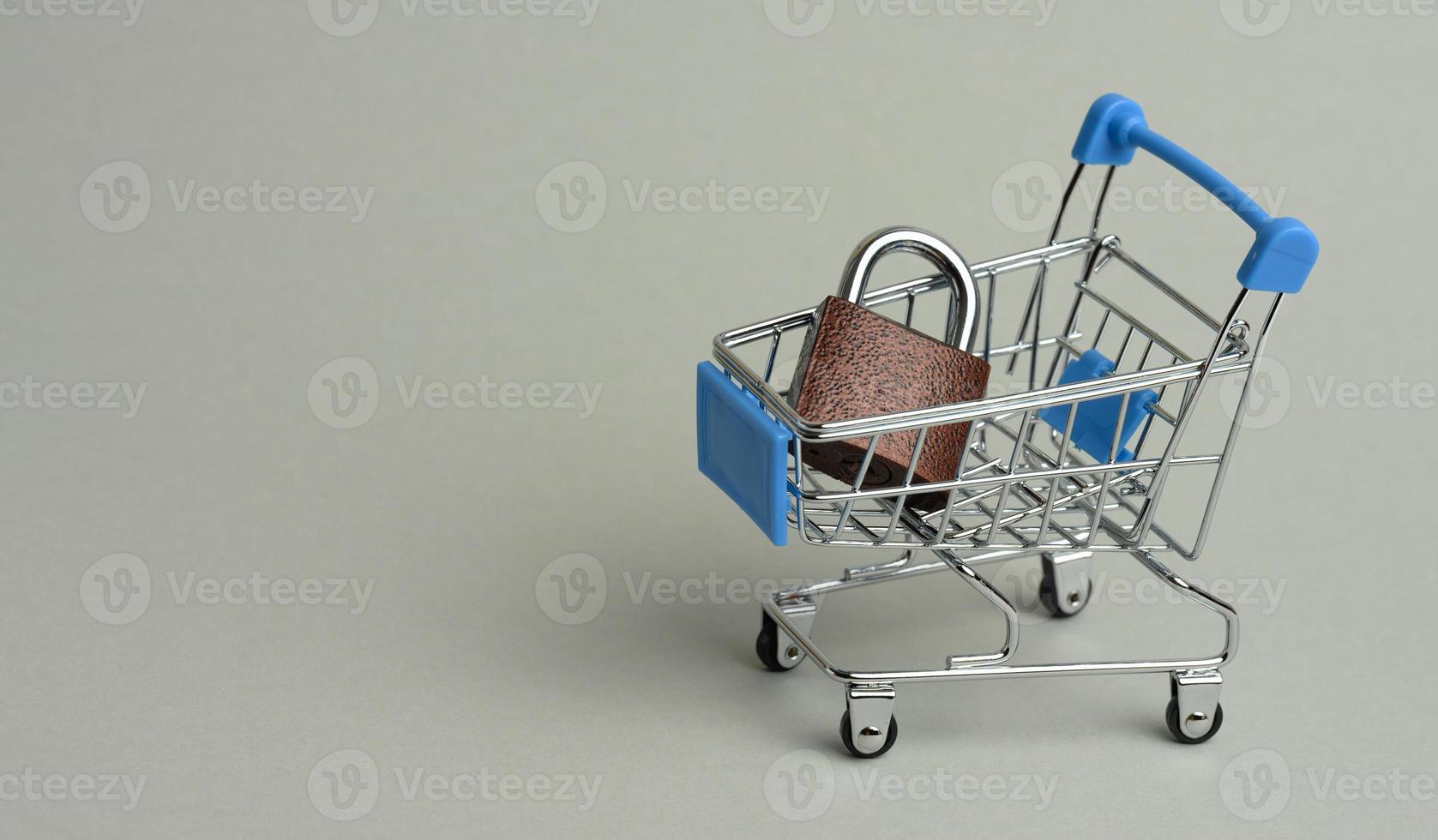 metallo serratura nel un' miniatura shopping carrello su un' grigio sfondo. sicuro in linea shopping concetto foto