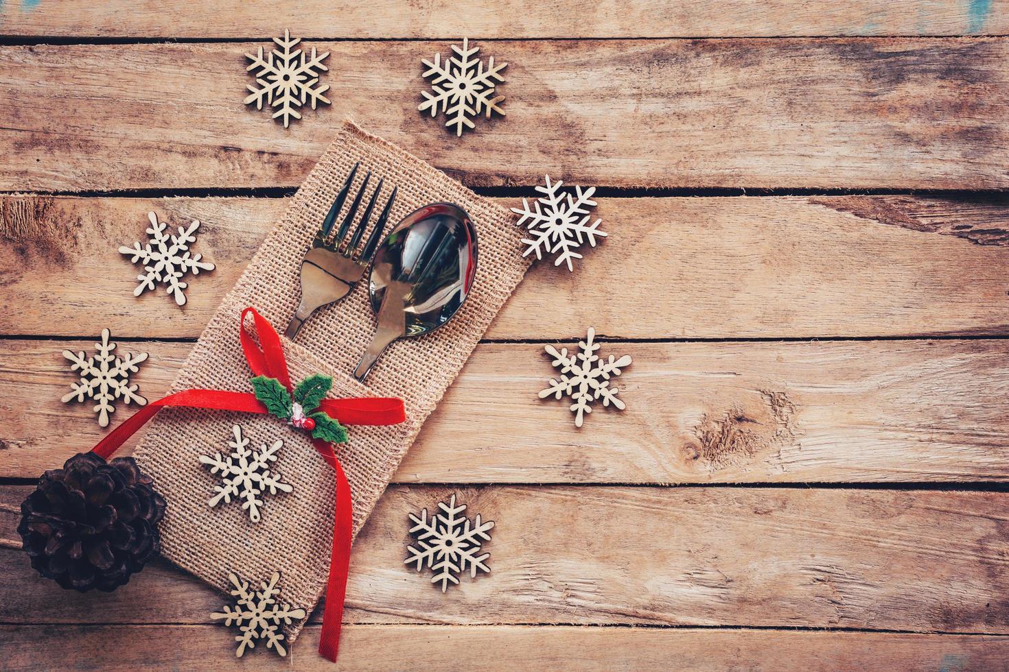 Natale tavolo posto ambientazione e argenteria, fiocchi di neve, pino coni su di legno sfondo con spazio. foto