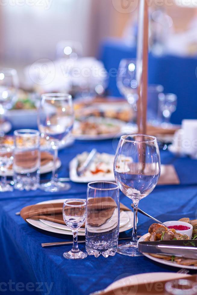 elegante tavolo ambientazione bianca piatti con tovaglioli su blu tovaglia, vasellame servito vuoto tavolo nel un' ristorante, vuoto occhiali, lusso vasellame concetto foto