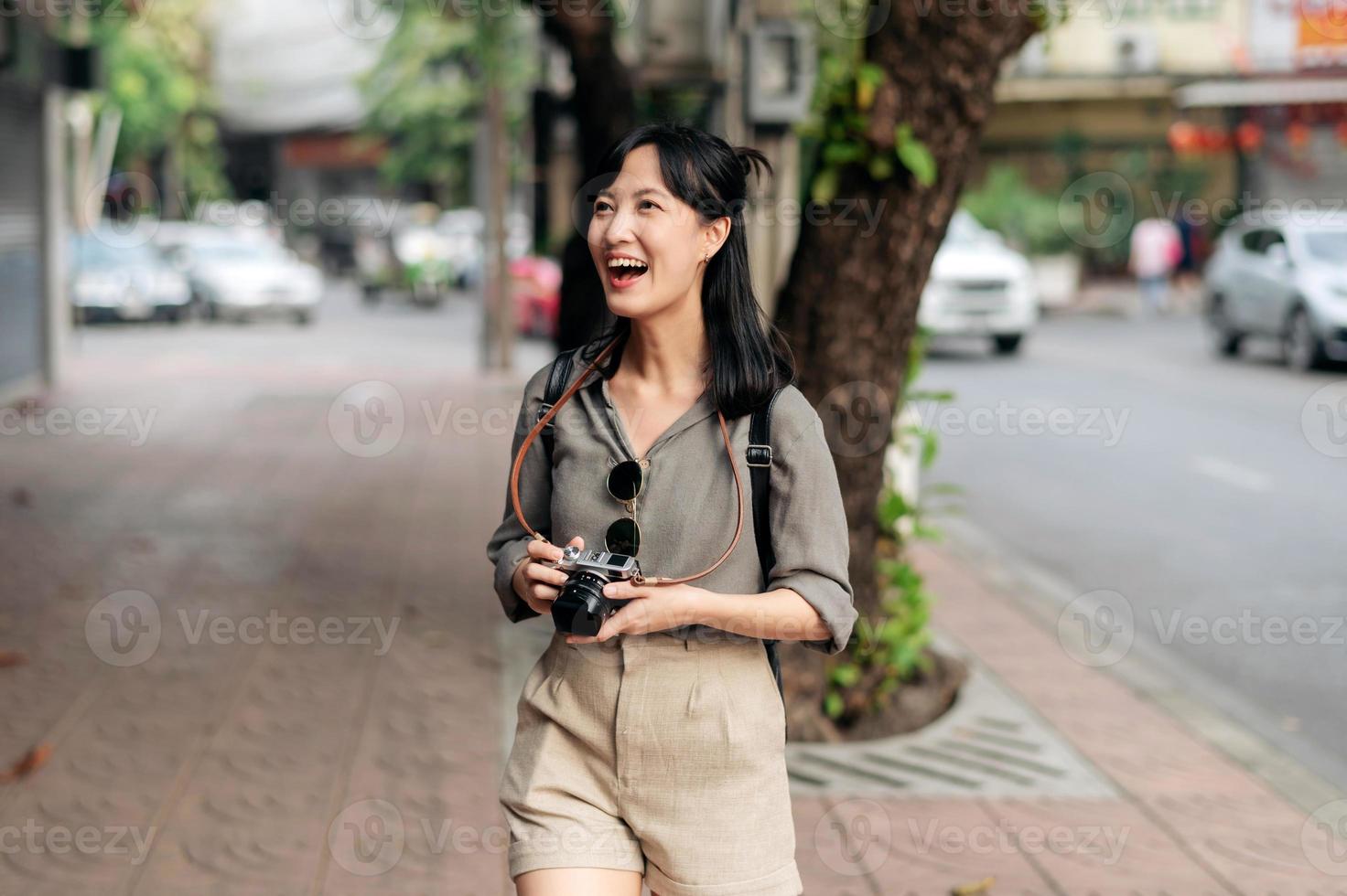 giovane asiatico donna zaino viaggiatore utilizzando digitale compatto telecamera, godendo strada culturale Locale posto e Sorridi. foto