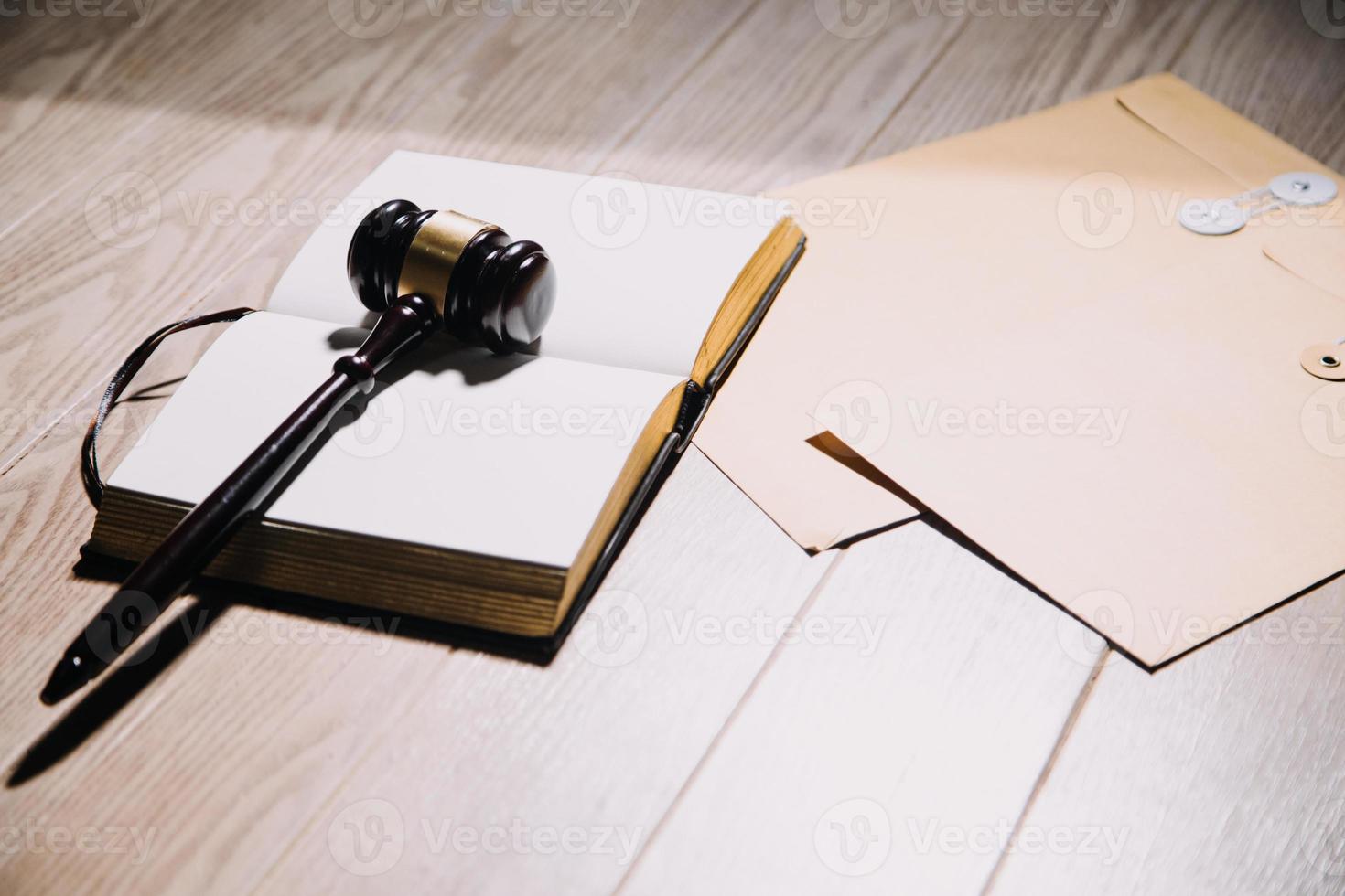 concetto di giustizia e diritto. giudice maschio in un'aula di tribunale con il martelletto, lavorando con computer e tastiera docking, occhiali, sul tavolo alla luce del mattino foto