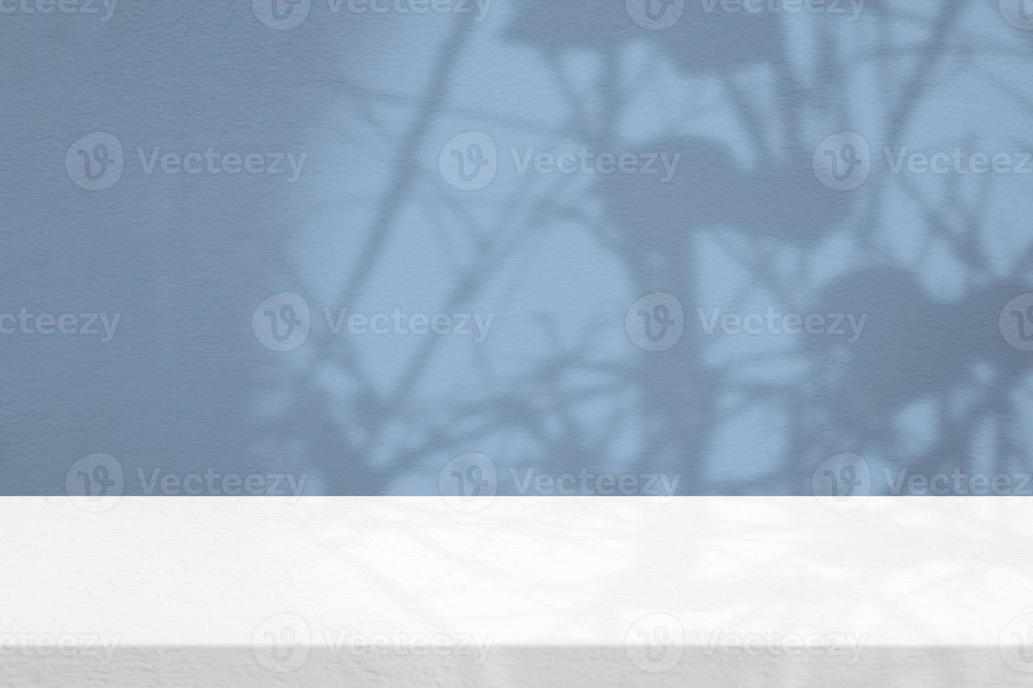bianca stucco tavolo con ombra di albero rami su calcestruzzo parete sfondo nel ceruleo blu tono, adatto per Prodotto presentazione sfondo, Schermo, e finto su. foto