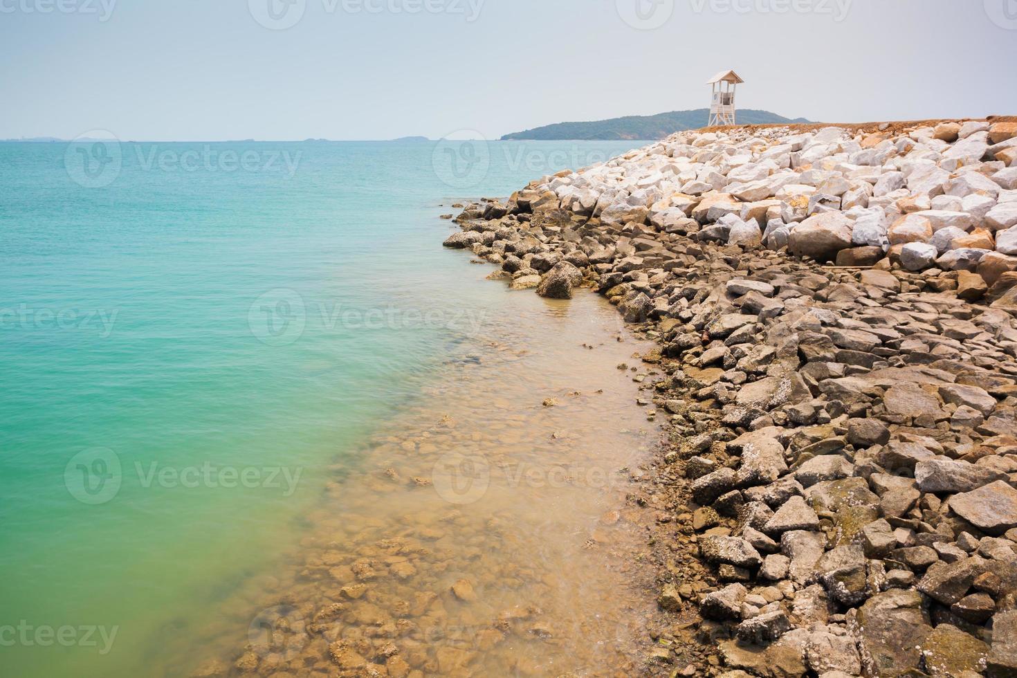 oceano blu brillante con una spiaggia rocciosa foto