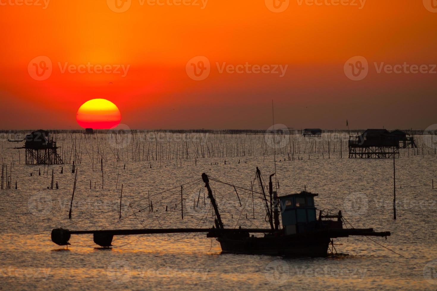 silhouette di barca da pesca e un tramonto foto