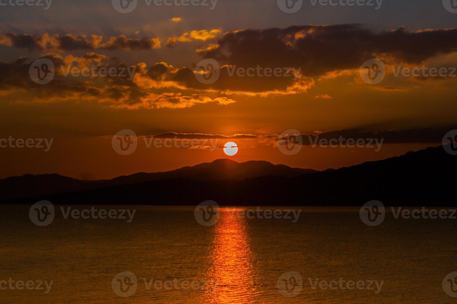 tramonto arancione su montagne e acqua foto