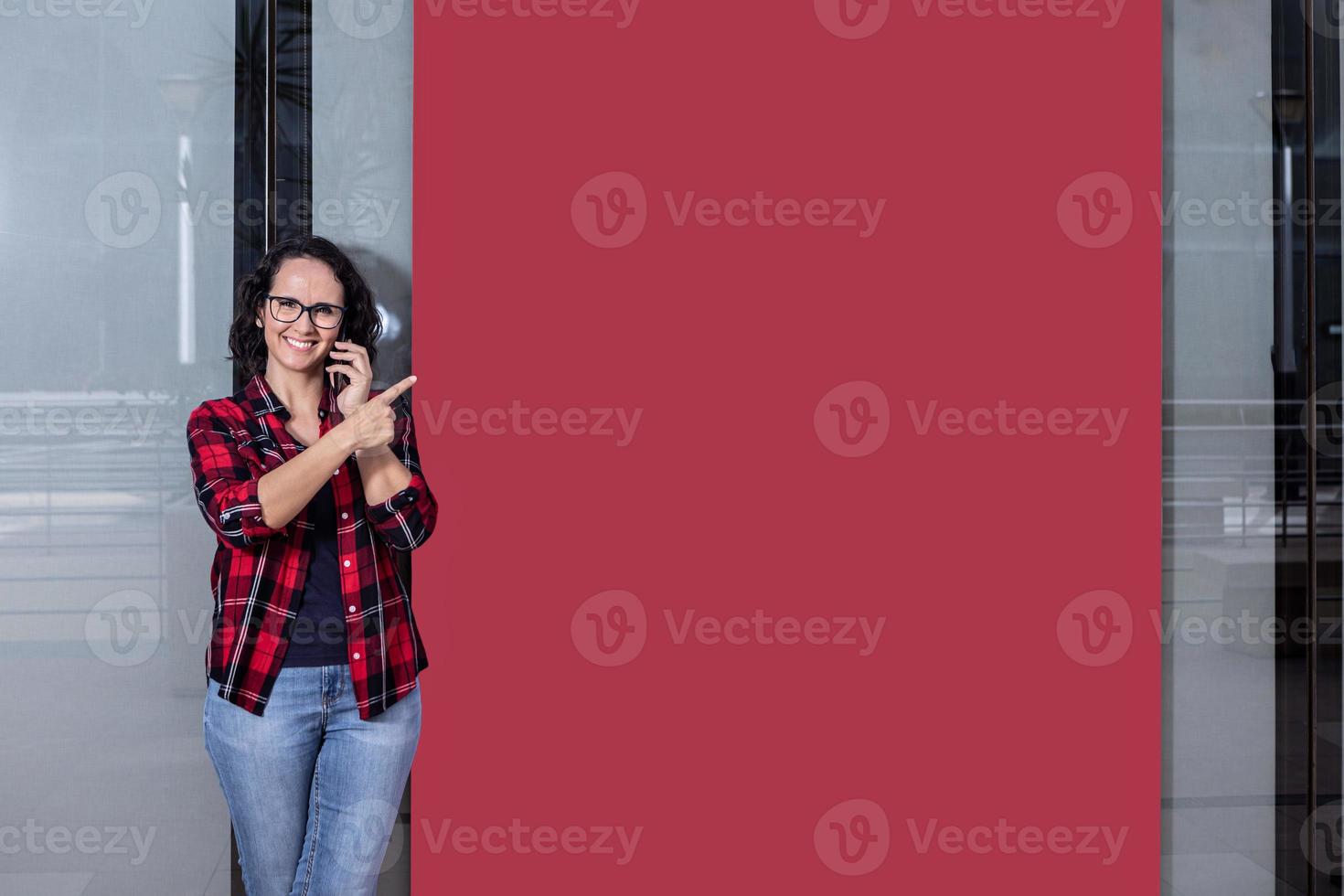 donna parlando con il mobile mentre puntamento per un' bandiera nel un' finestra negozio foto