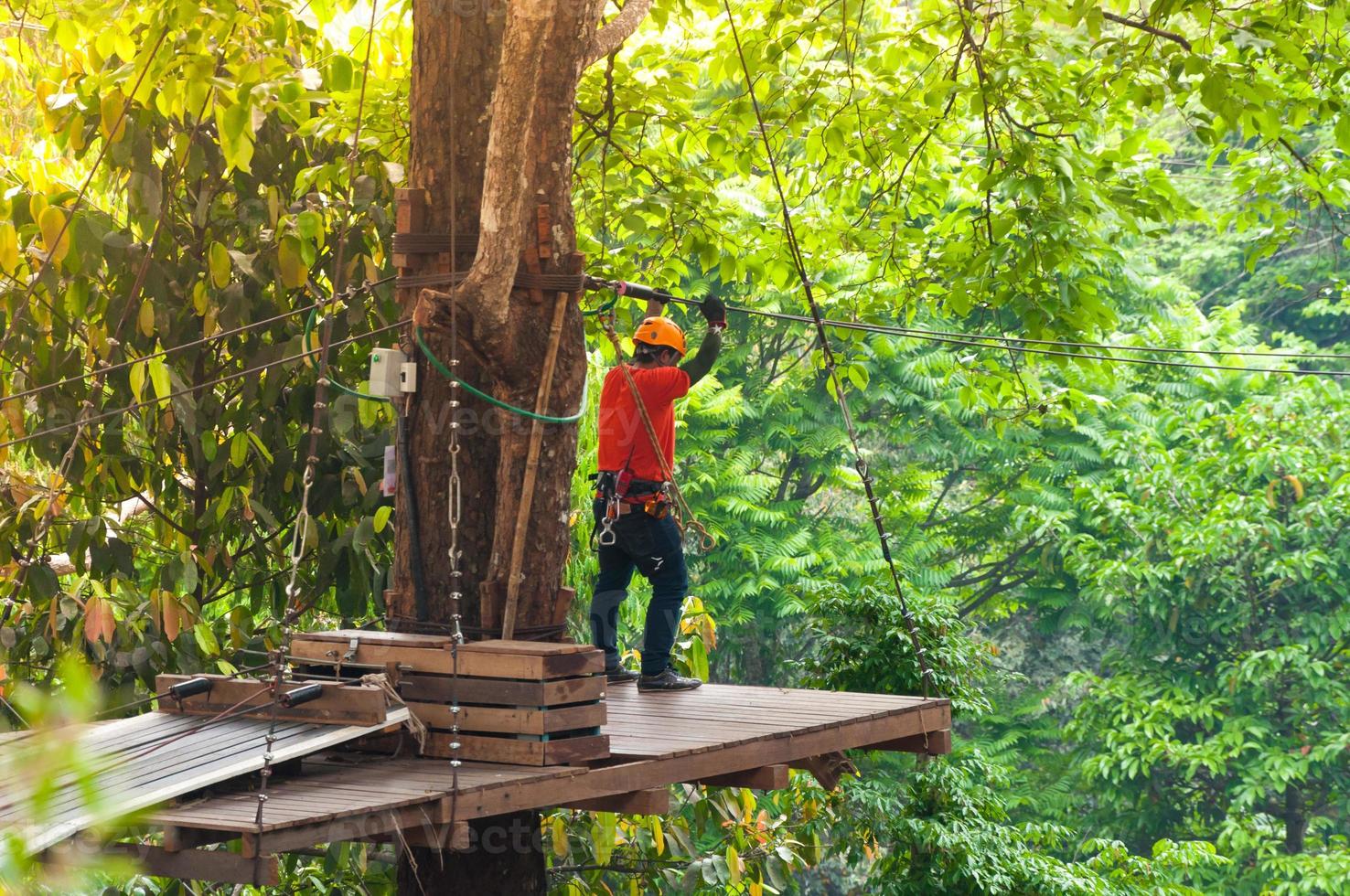 avventura Teleferica alto filo parco - persone su corso nel montagna casco e sicurezza attrezzatura, pronta per scendere su Teleferica nel foresta, estremo sport foto