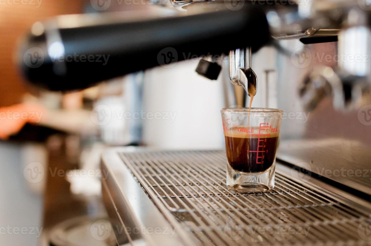 avvicinamento nero caffè nel misurazione tazza mettere su caffè creatore, caffè macchina fabbricazione caffè espresso foto