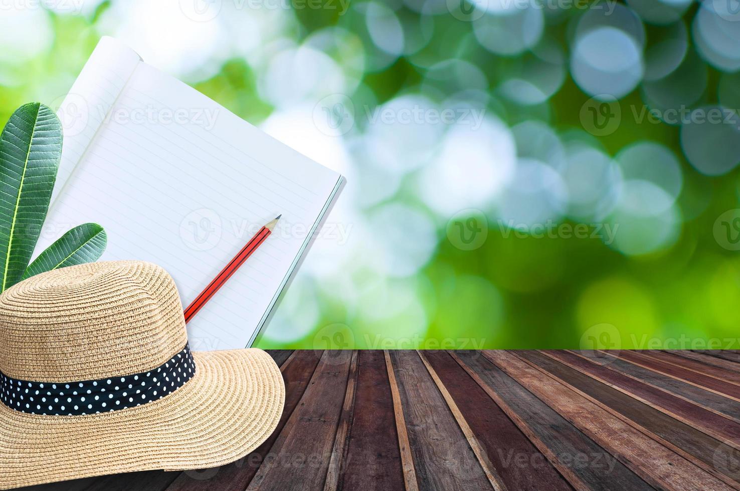 taccuino con matita e cannuccia cappello su di legno tavolo con verde bokeh sfondo foto