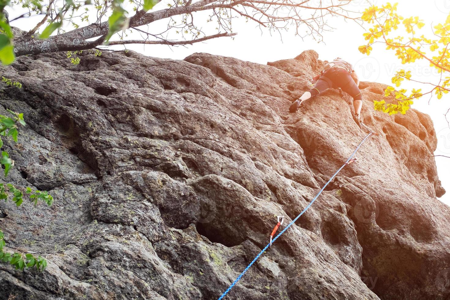maschio scalatore, giovane uomo-scalatore arrampicata un' difficile itinerario su un' scogliera. scalatore si arrampica un' roccioso parete. con sicurezza corda su il roccia foto