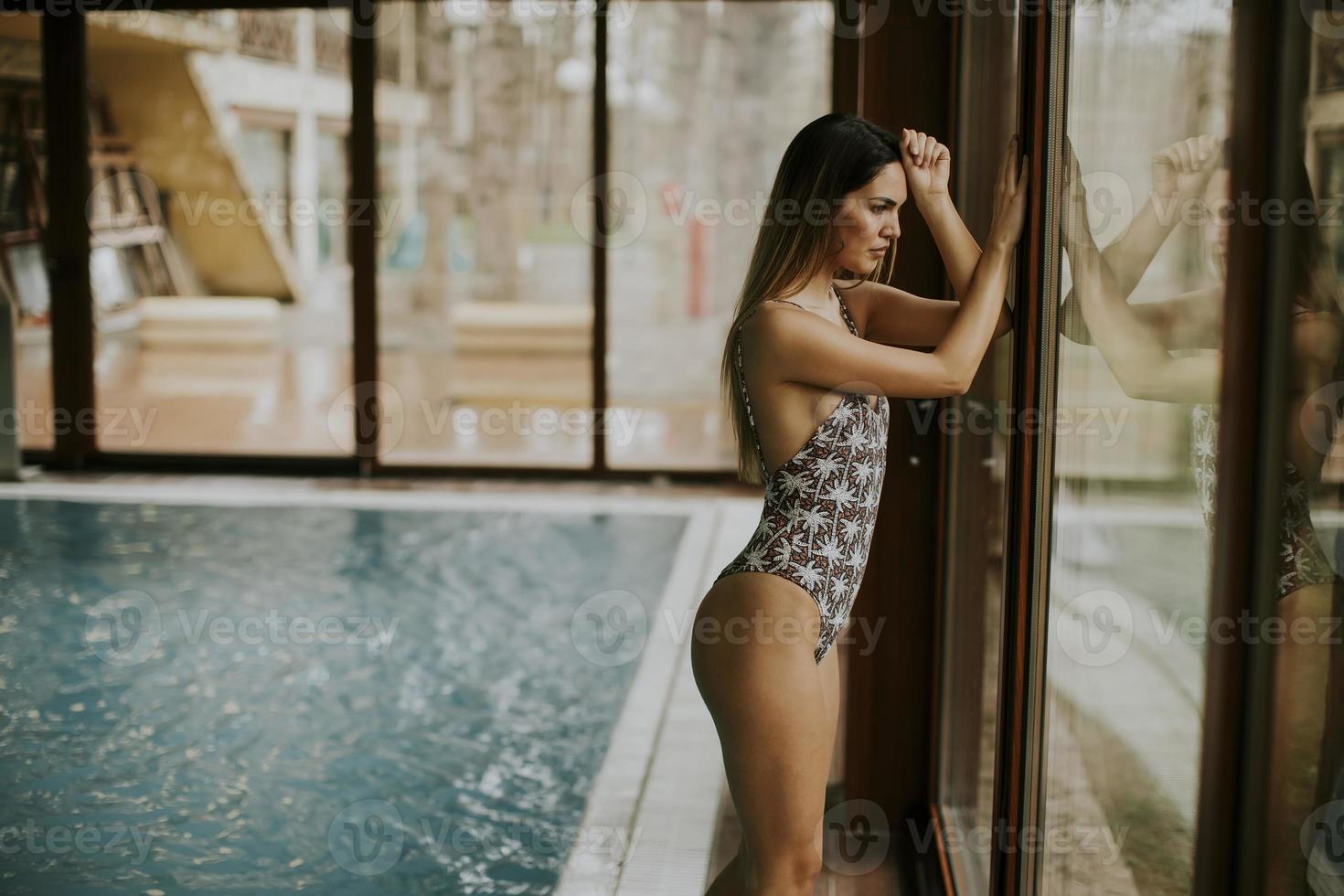 bella giovane donna in piedi vicino alla finestra in piscina foto