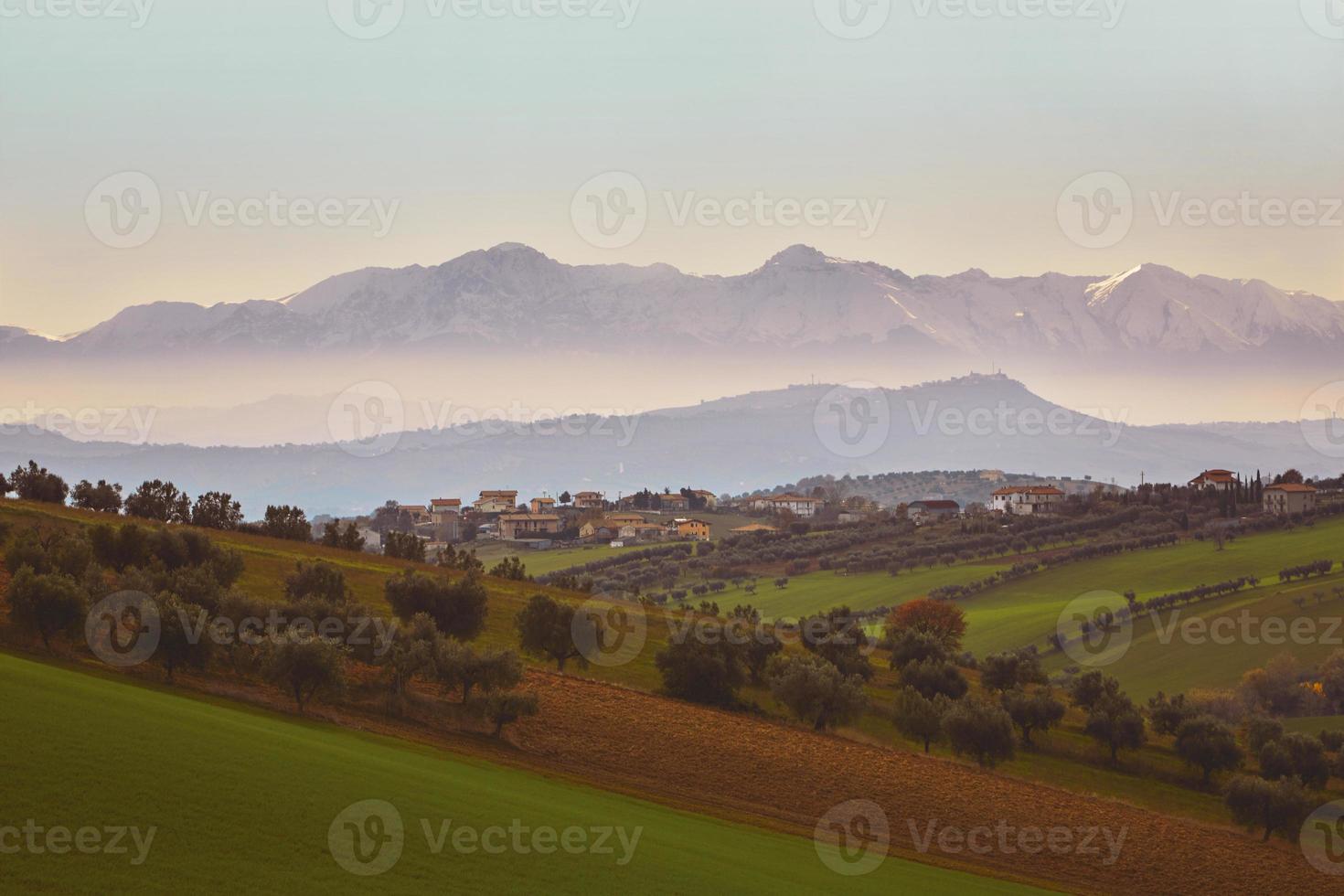 panorama della campagna italiana con montagne nebbiose e innevate foto