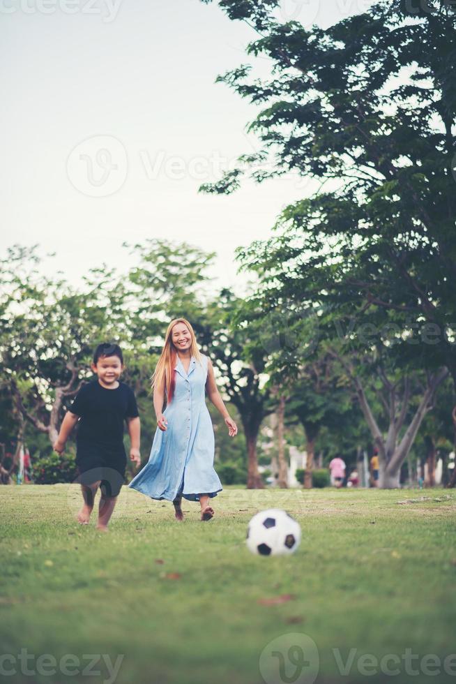 ragazzino che gioca a calcio con la madre nel parco foto