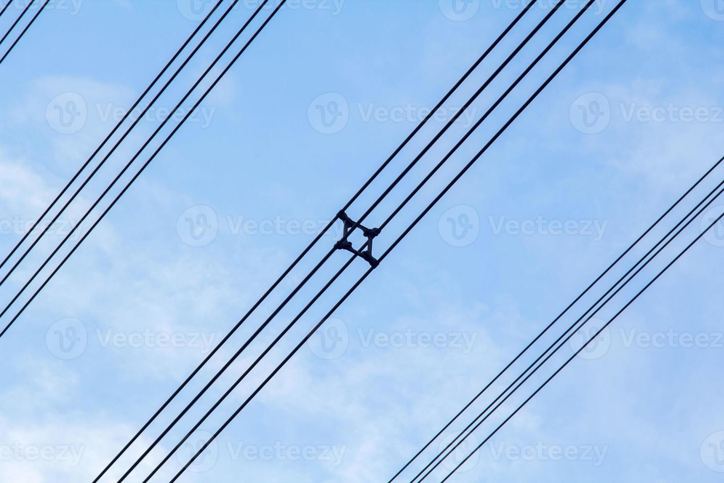 alta tensione e isolato cavi sospeso nel il blu cielo siamo cavi quello trasportare elettricità e elettricità per persone e molti industriale impianti e aziende quello bisogno elettricità. foto