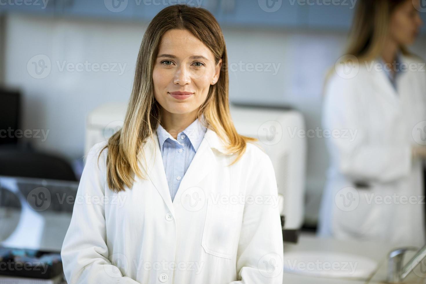 scienziato femminile in camice bianco in piedi nel laboratorio biomedico foto