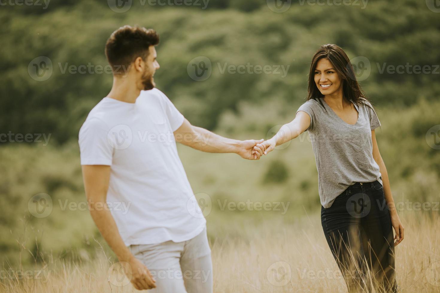 felice giovane coppia innamorata camminando attraverso il campo in erba foto