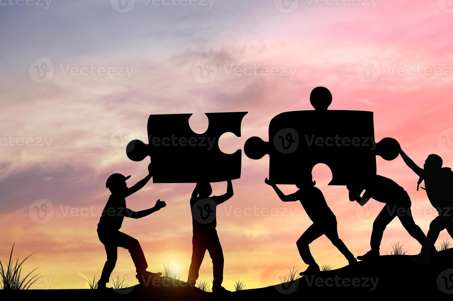 silhouette di persone che aiutano a collegare i pezzi del puzzle foto