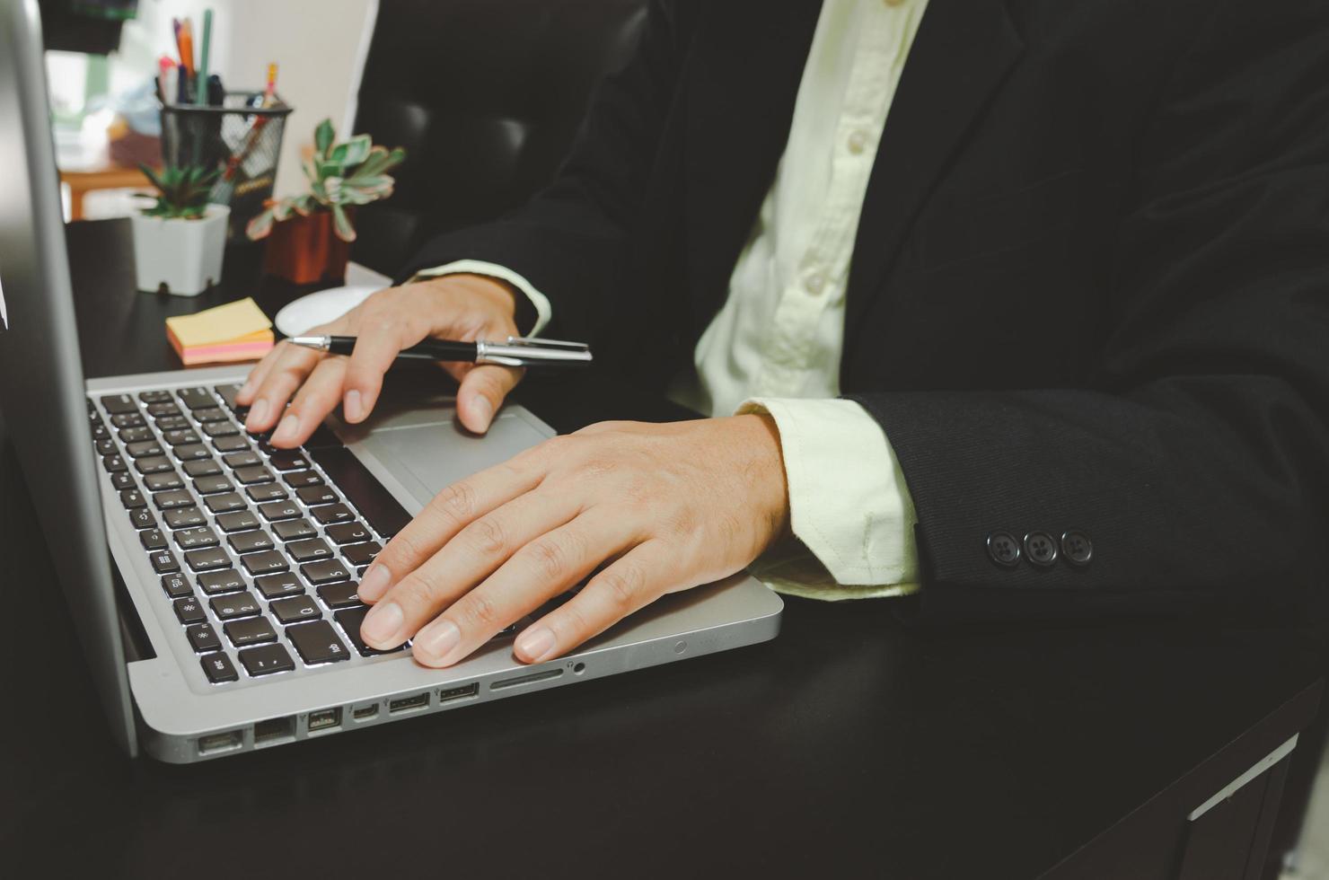 la mano di un uomo d'affari su un computer e in possesso di una penna foto