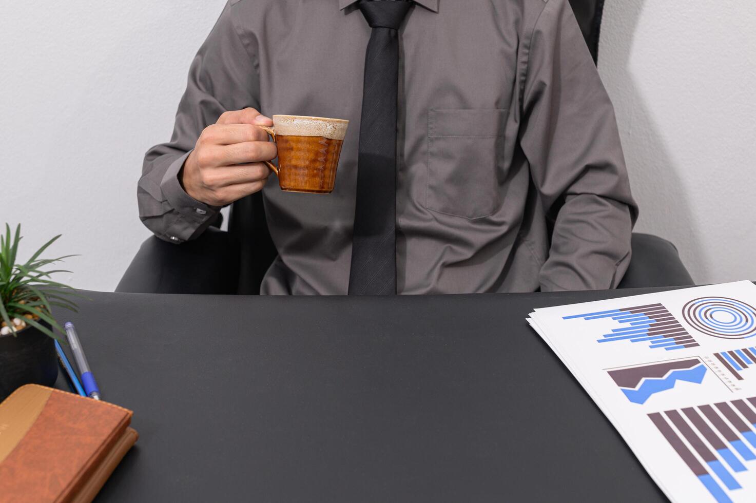 un uomo d'affari che beve caffè alla sua scrivania foto