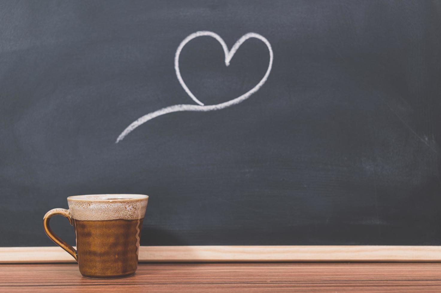 tazza di caffè e cuore scarabocchio sulla lavagna foto