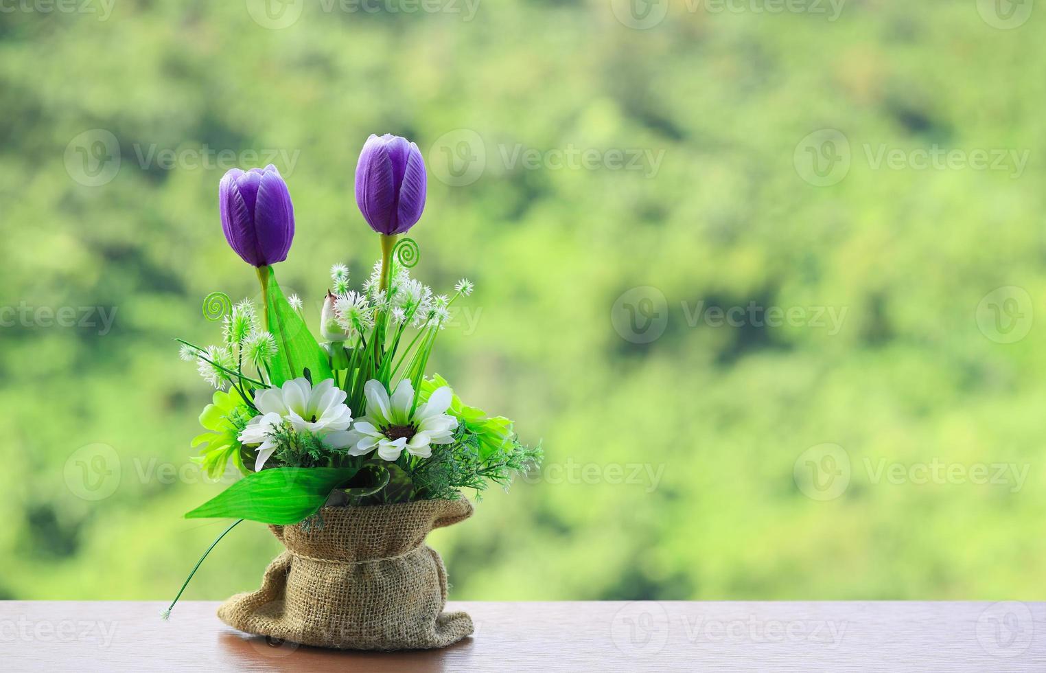 fiori viola nel sacco di iuta sul tavolo di legno con sfondo natura vaga foto