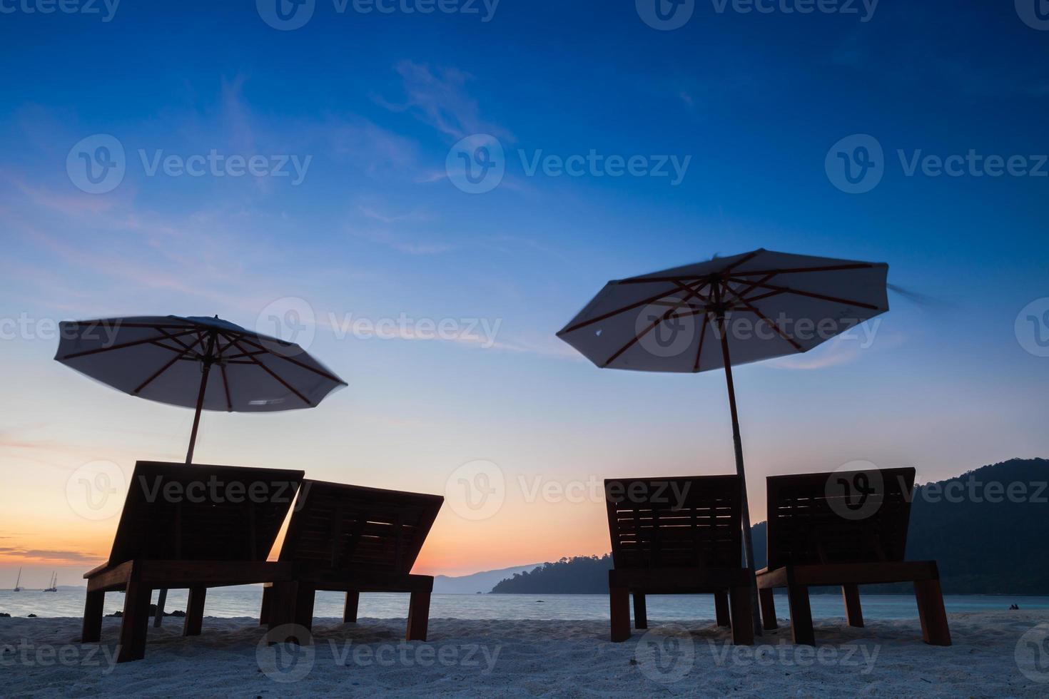 silhouette di sedie e ombrelloni al tramonto foto