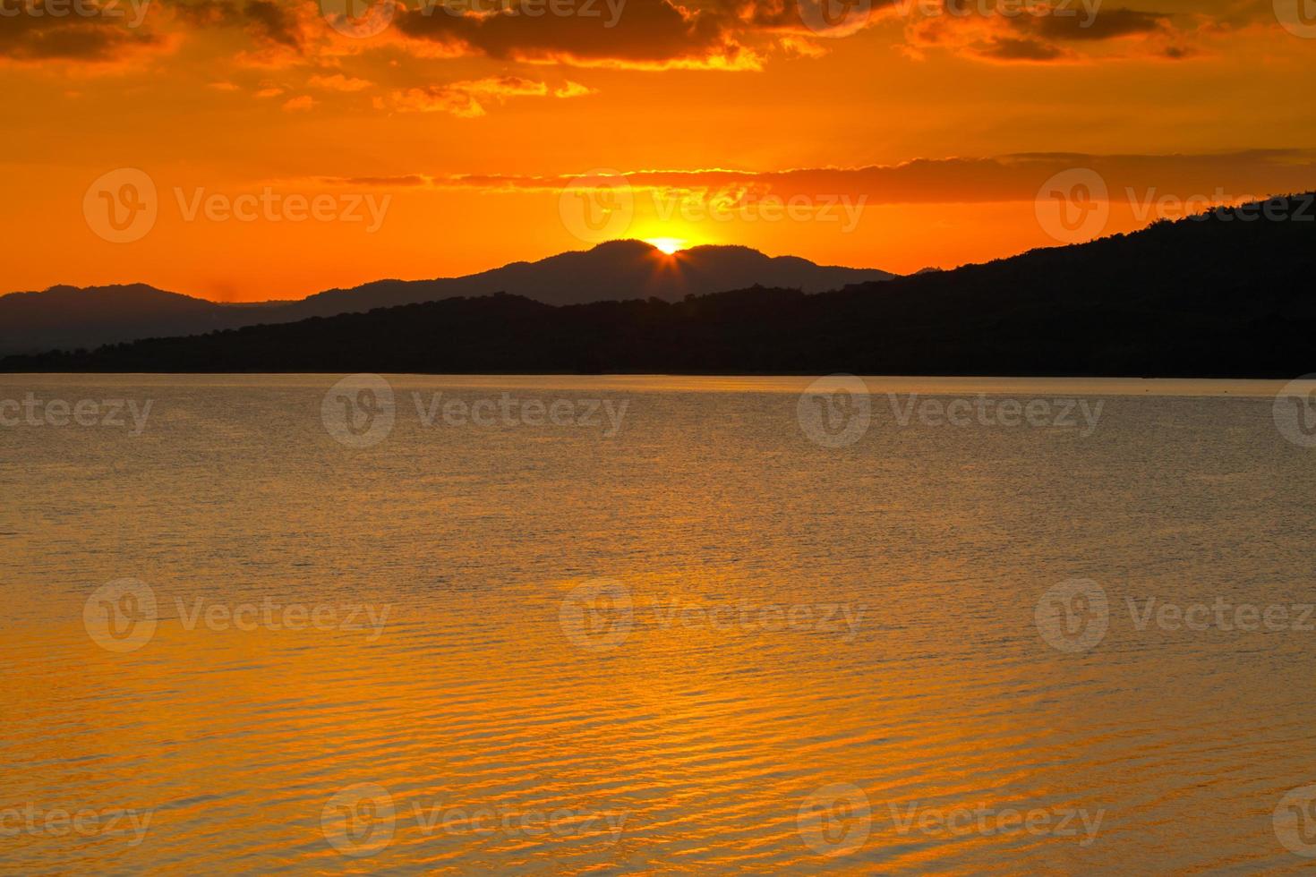 vibrante tramonto arancione sulle montagne e sull'oceano foto