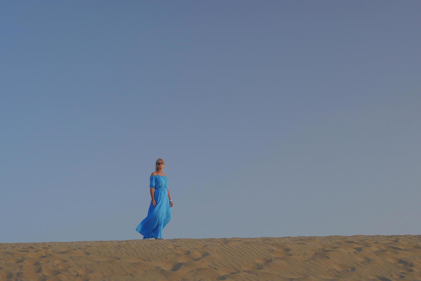 donna che cammina sulle dune di sabbia foto
